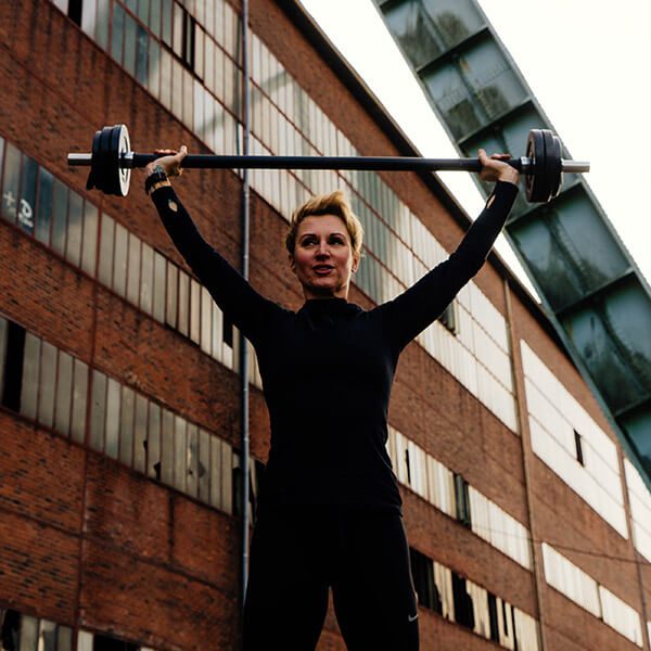 Krafttraining mit der Langhantel vor Industriekulisse